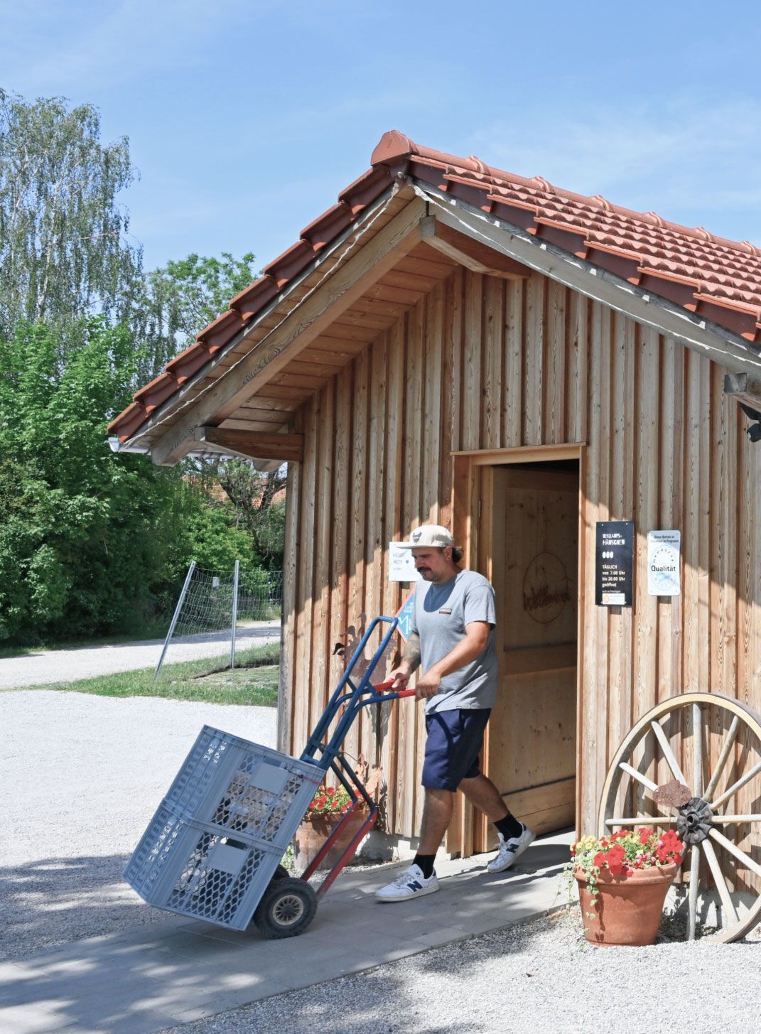 Nikolaus Walter, farmer at Gut Hollern and a regional supplier to Munich Airport, moves stacked crates on a hand truck in front of a wooden sales hut.
